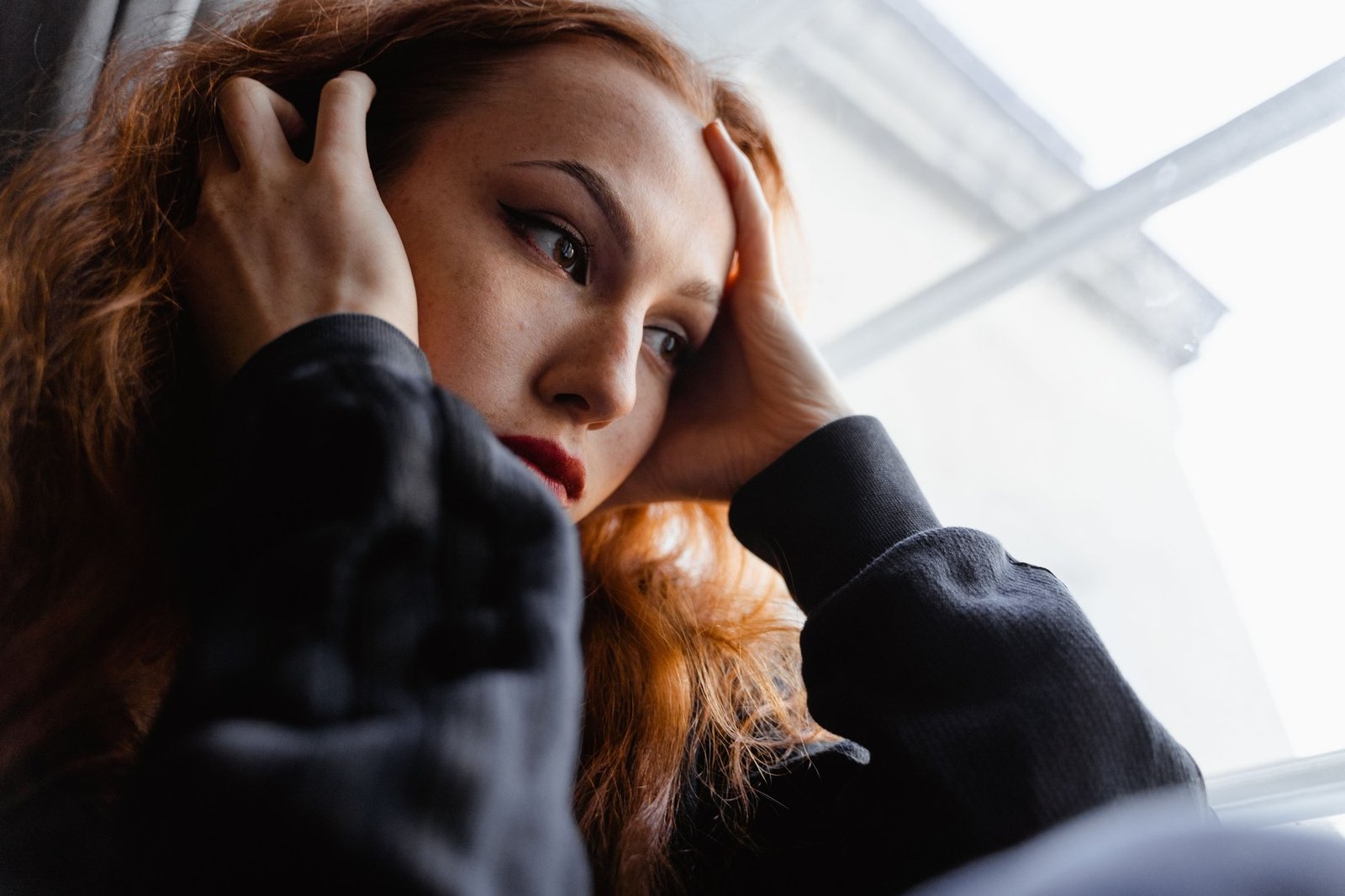 A person holding their head in low light