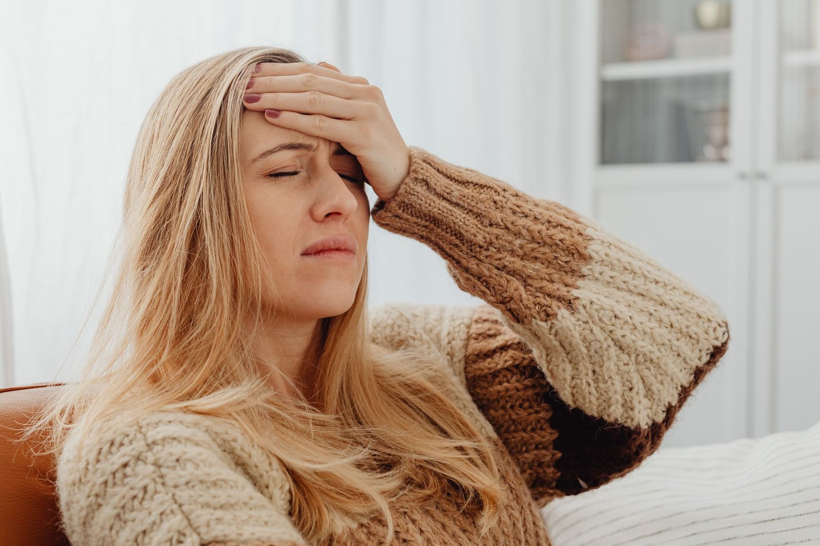 A person in low light pressing both hands to the temples during a headache