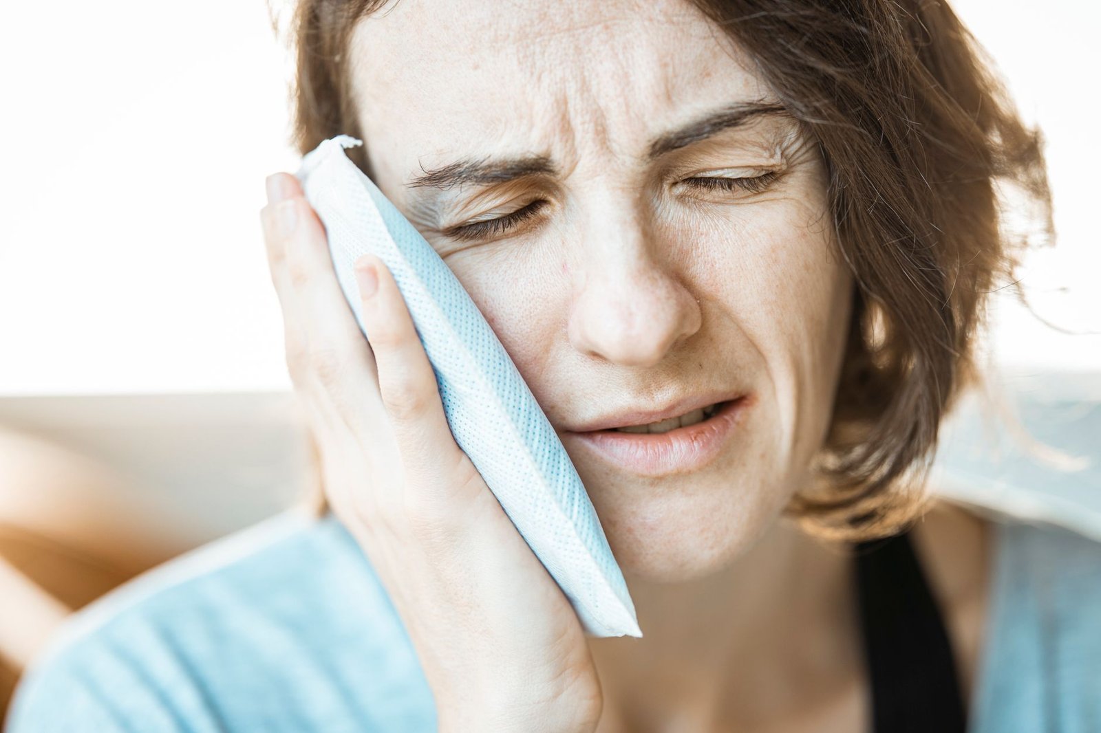A person holding the side of the jaw in front of the ear, where temporomandibular pain is felt